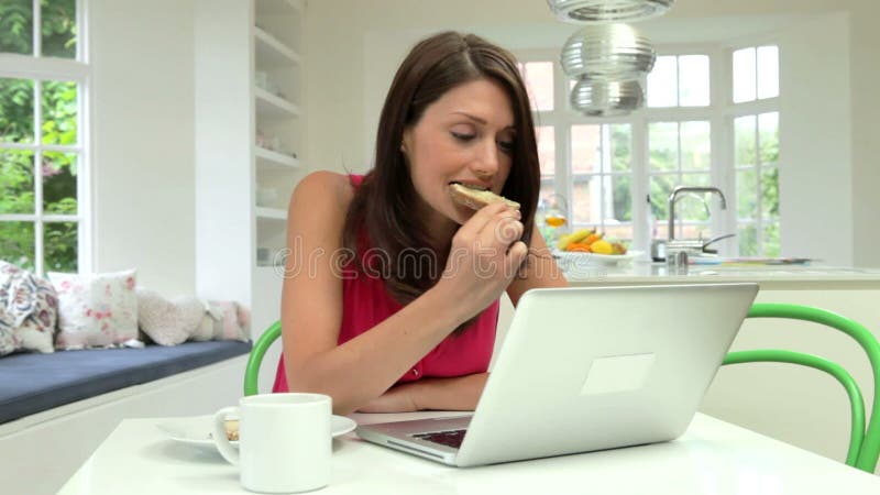 Femme hispanique à l'aide de l'ordinateur portable dans la cuisine à la maison banque de vidéos