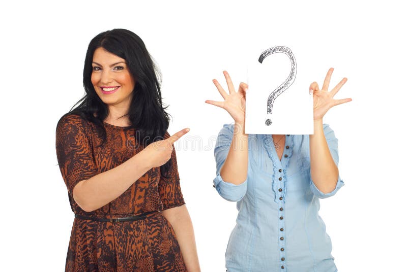 Happy smiling woman pointing to her unknown friend who hold a question mark in front of face isolated on white background. Happy smiling woman pointing to her unknown friend who hold a question mark in front of face isolated on white background