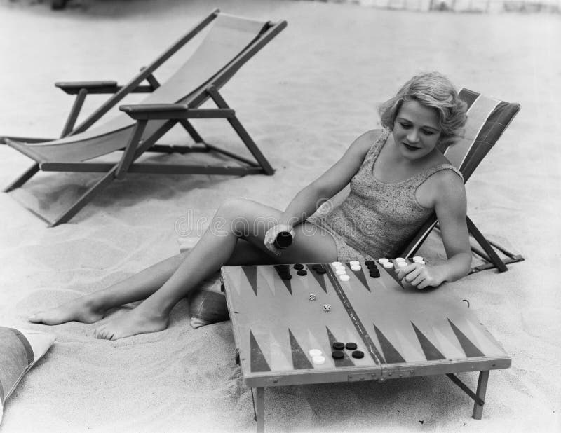 Femme jouant le backgammon sur la plage (toutes les personnes représentées ne sont pas plus long vivantes et aucun domaine n'exis photos stock Femme jouant le backgammon sur la plage (toutes les personnes représentées ne sont pas plus long vivantes et aucun domaine n'exis photos stock
