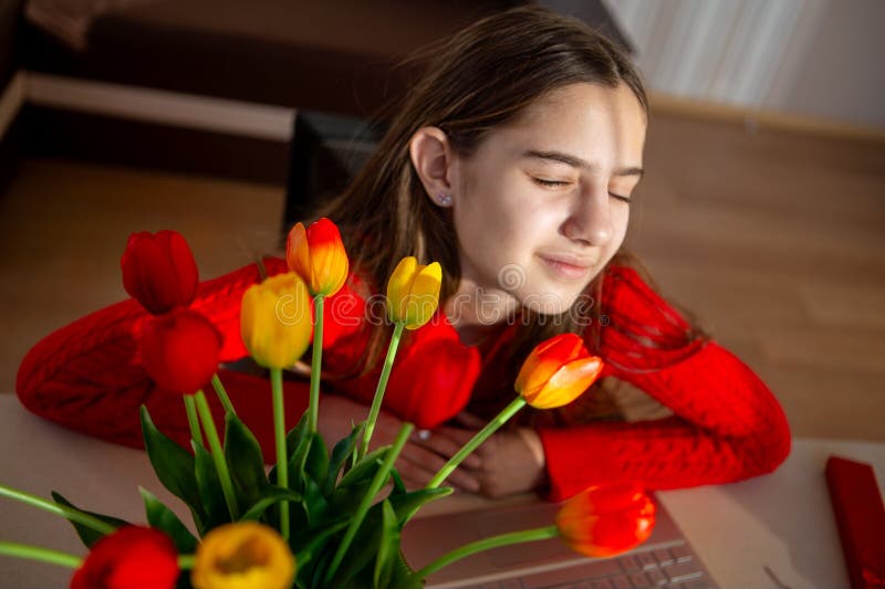 Femme jouissant paisiblement des tulipes à la lumière du jour. Une jeune femme en chandail rouge se penche sur un bouquet vibrant image stock