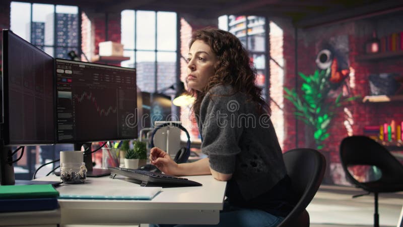 Femme jour trader examine les graphiques boursiers sur deux moniteurs banque de vidéos