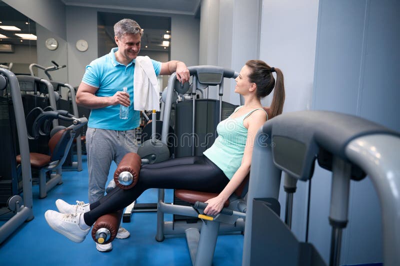Femme joyeuse faisant de l'entraînement en bas du corps pendant la conversation avec le partenaire de fitness images stock