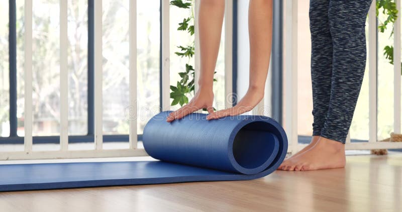 Femme les mains roulé tapis de yoga sur le sol de la salle de gym dans la salle d'entraînement de yoga. home entraînement femme fe