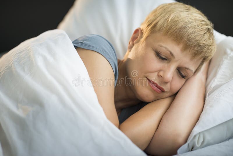 Femme mûre dormant dans le lit image libre de droits Femme mûre dormant dans le lit image libre de droits