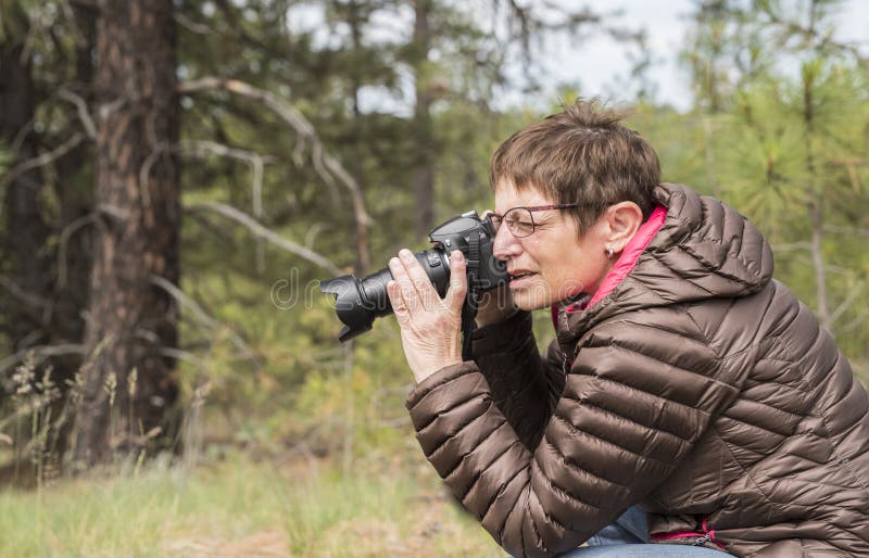 Femme mûre heureuse prenant des photos avec un appareil-photo de Digital DSLR images libres de droits Femme mûre heureuse prenant des photos avec un appareil-photo de Digital DSLR images libres de droits