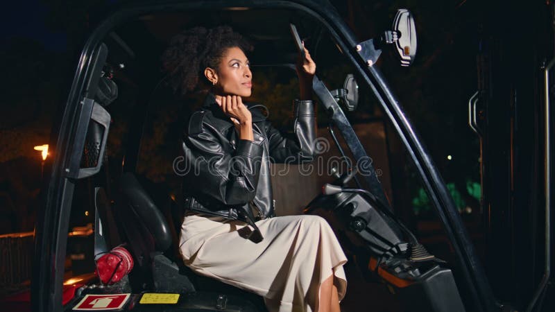 Femme magnifique appliquer maquillage dans chariot élévateur à fourche la nuit. femme africaine confiante banque de vidéos
