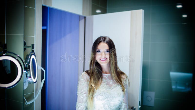Femme magnifique de brune avec de longs cheveux et yeux bleus se regardant dans le miroir images stock Femme magnifique de brune avec de longs cheveux et yeux bleus se regardant dans le miroir images stock