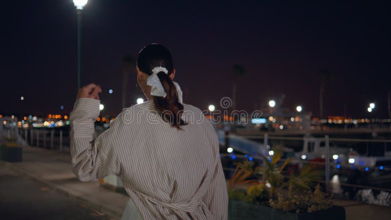 Femme marcher le quai de nuit profiter seul des feux de rue. dame à la date clips vidéos