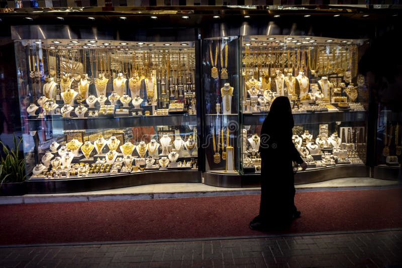 Femme musulmane dans la vue de burqa les fenêtres dans le souk d'or à Dubaï photo stock Femme musulmane dans la vue de burqa les fenêtres dans le souk d'or à Dubaï photo stock