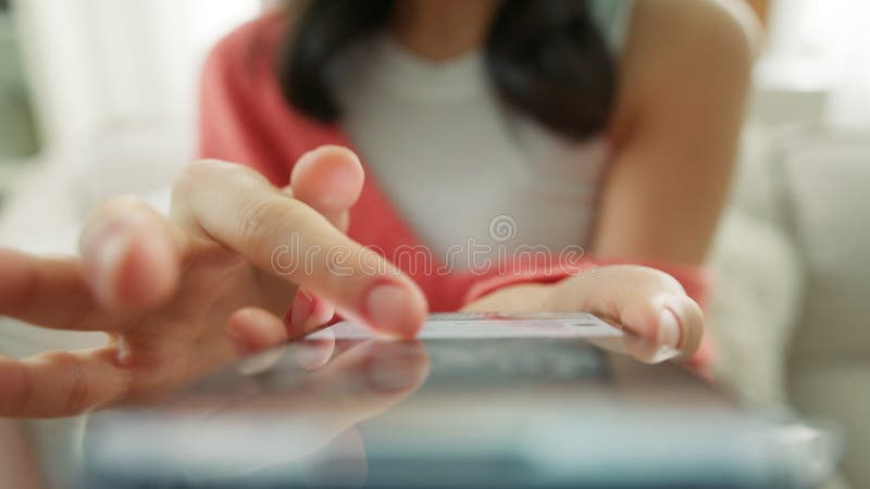 Femme méconnaissable en chandail corail orange assis sur un canapé avec smartphone 4k banque de vidéos