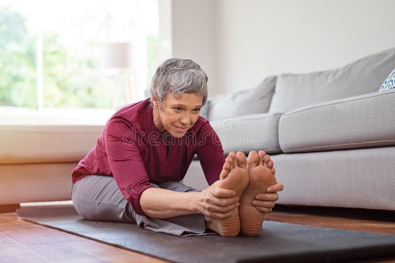 Femme mûre faisant l'exercice de yoga à la maison photo libre de droits Femme mûre faisant l'exercice de yoga à la maison photo libre de droits