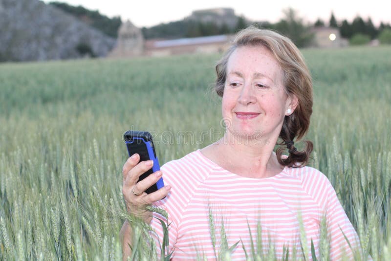 Femme mûre à l'aide du téléphone portable en nature images libres de droits Femme mûre à l'aide du téléphone portable en nature images libres de droits