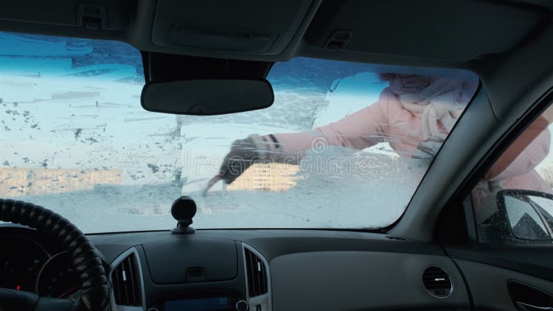 Une Fille Nettoie Un Pare-brise Glacé Dans Une Voiture Avec Un Grattoir