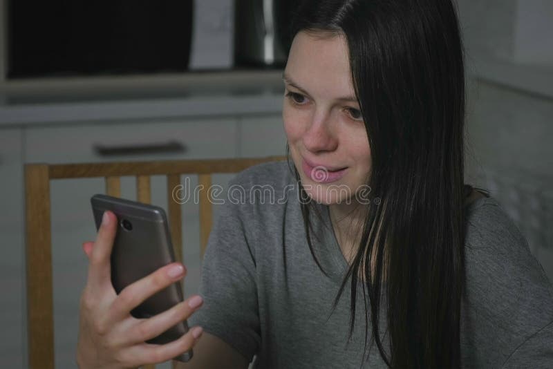 Femme observant une vidéo terrible à un téléphone portable dans la cuisine la nuit image libre de droits Femme observant une vidéo terrible à un téléphone portable dans la cuisine la nuit image libre de droits