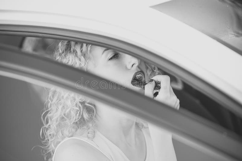 Femme ou fille appliquant le rouge à lèvres rouge sur des lèvres dans la voiture photographie stock libre de droits Femme ou fille appliquant le rouge à lèvres rouge sur des lèvres dans la voiture photographie stock libre de droits