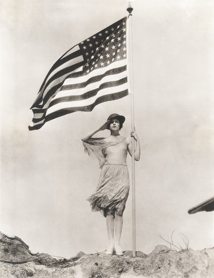 Femme patriote tenant le drapeau américain et la salutation images stock Femme patriote tenant le drapeau américain et la salutation images stock