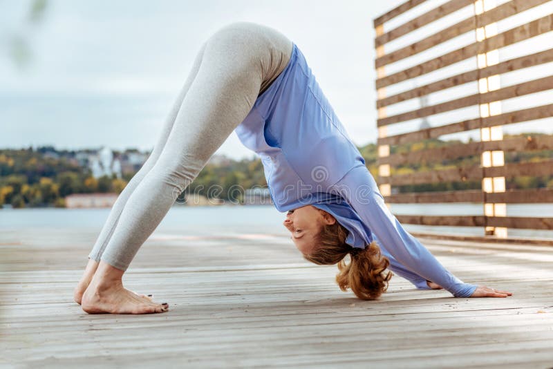 Femme pratiquant concentratedly la pose orientée vers le bas de yoga de chien image libre de droits Femme pratiquant concentratedly la pose orientée vers le bas de yoga de chien image libre de droits