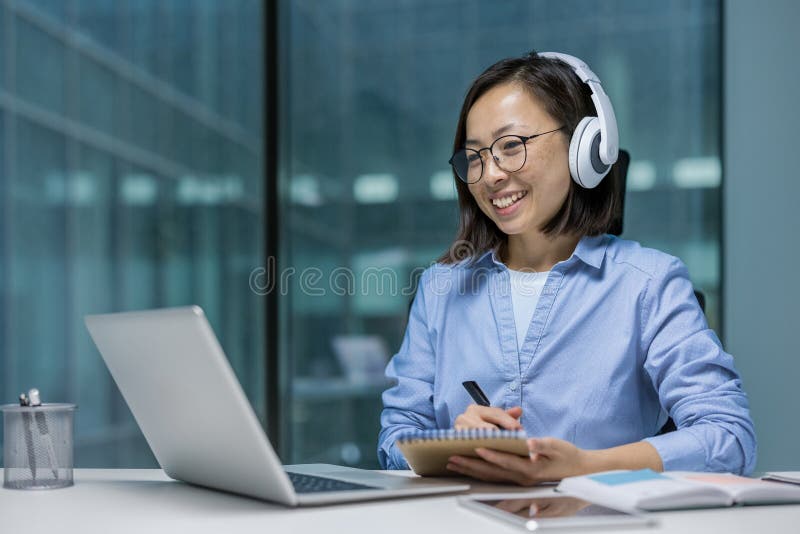 Femme regardant en ligne vidéo cours de formation conférence à l'intérieur du bureau. Travailleur Office asiatique dans les casque photos stock