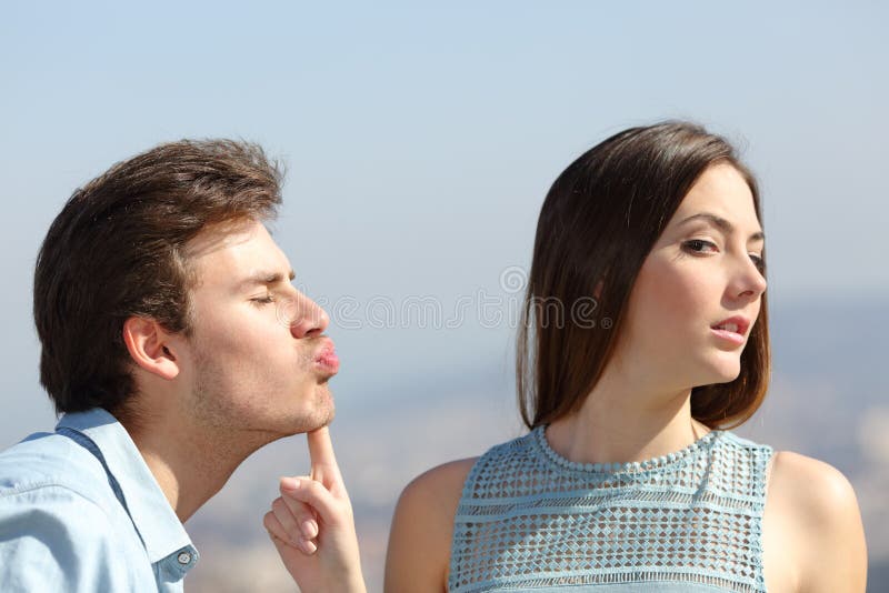 Woman rejecting a friend kiss in a sunny day. Woman rejecting a friend kiss in a sunny day