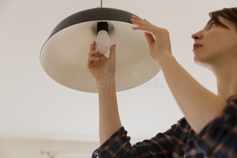 Femme remplaçant l'ampoule à la maison Changement de lampe de l'économie d'énergie LED photo stock Femme remplaçant l'ampoule à la maison Changement de lampe de l'économie d'énergie LED photo stock