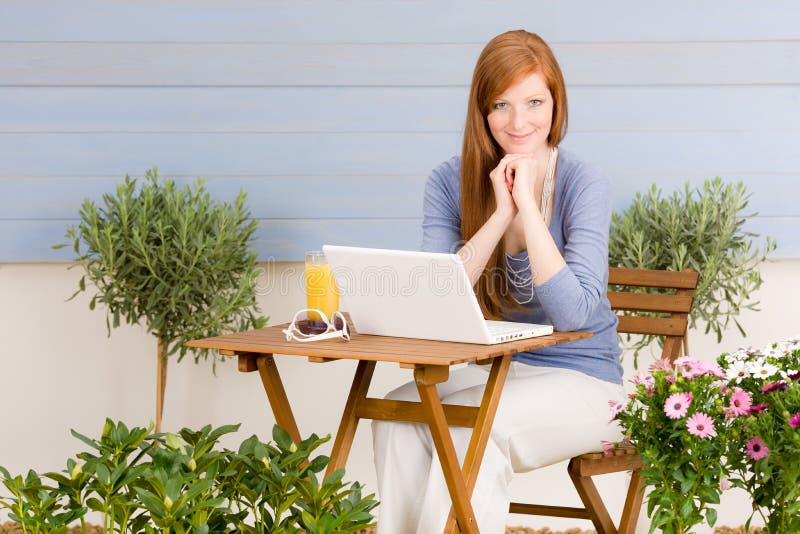 Femme rousse de terrasse d'été avec l'ordinateur portatif