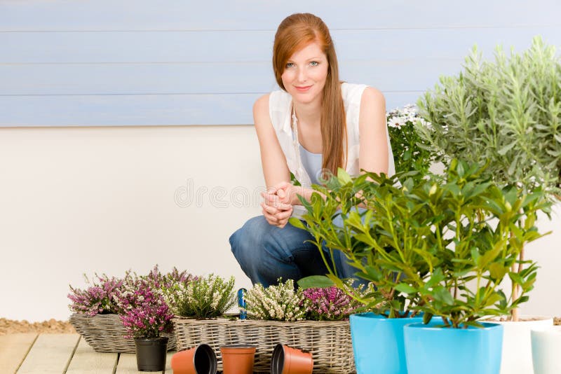 Femme rousse de terrasse de jardin d'été avec des fleurs