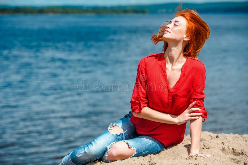 Femme rousse joyeuse effleurant ses cheveux dans le ciel photos stock