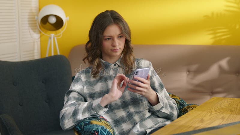 Femme réfléchie utilisant un smartphone à la maison. message de saisie de fille sur téléphone portable clips vidéos