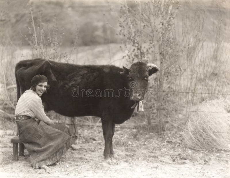 Femme s'asseyant par la vache