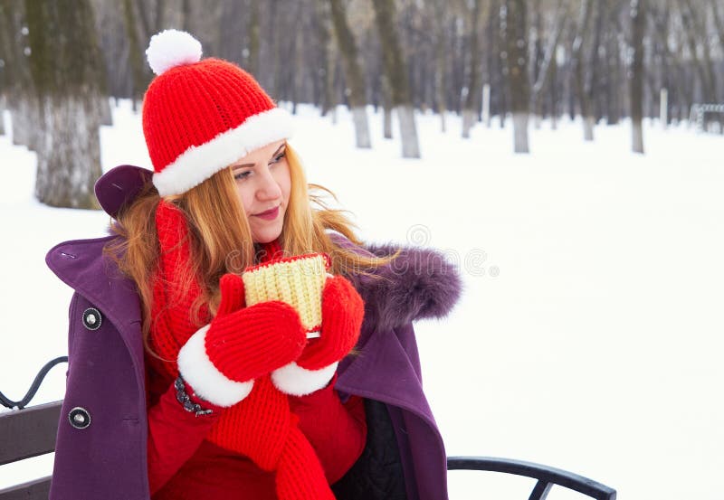 Femme s'asseyant sur le banc en parc de neige d'hiver et café ou thé chaud potable photos stock Femme s'asseyant sur le banc en parc de neige d'hiver et café ou thé chaud potable photos stock