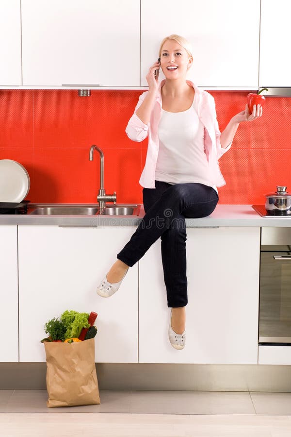 Femme s'asseyant sur le compteur dans la cuisine photos stock Femme s'asseyant sur le compteur dans la cuisine photos stock