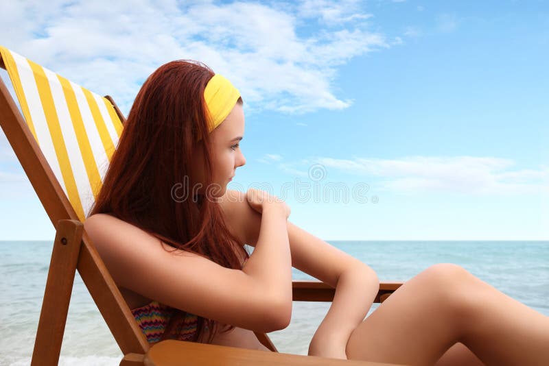 Femme s'asseyant à la plage vous avez mis la protection solaire images stock Femme s'asseyant à la plage vous avez mis la protection solaire images stock