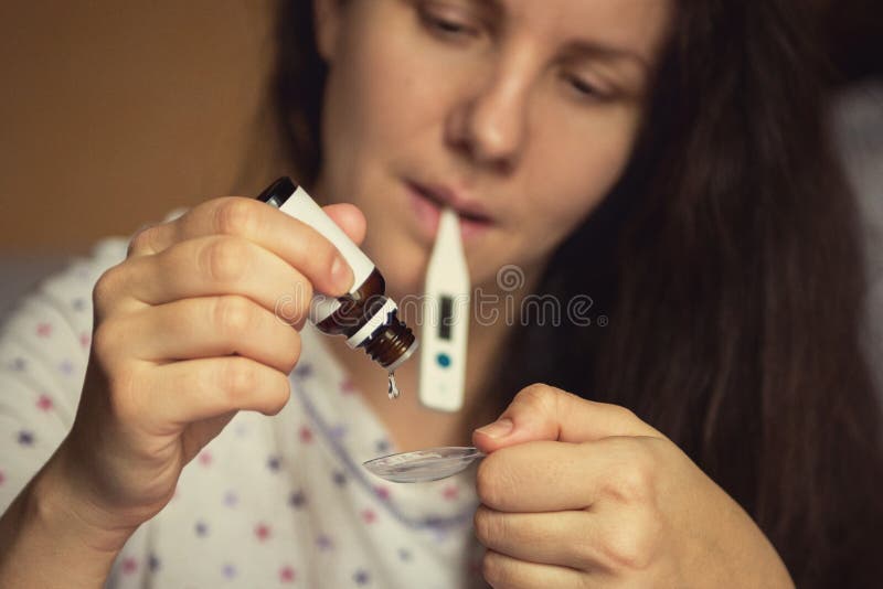 Femme s'égouttant la médecine curative dans une cuillère photo libre de droits Femme s'égouttant la médecine curative dans une cuillère photo libre de droits