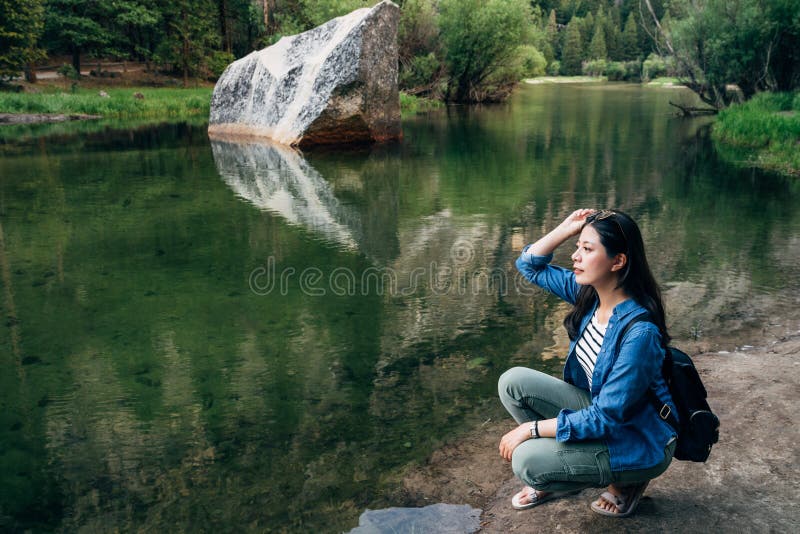 Femme se mettant à genoux en bas de la détente au lac de miroir images stock