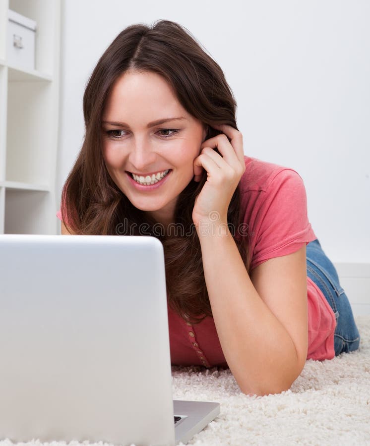 Femme se trouvant sur le plancher devant l'ordinateur portable image libre de droits Femme se trouvant sur le plancher devant l'ordinateur portable image libre de droits