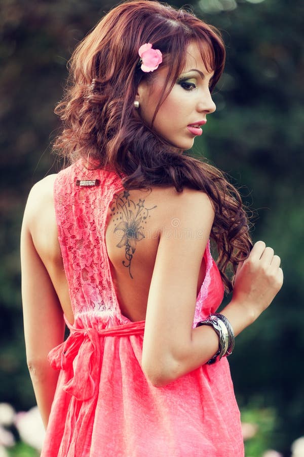 Femme sensuelle avec le tatouage sur elle en arrière photographie stock Femme sensuelle avec le tatouage sur elle en arrière photographie stock