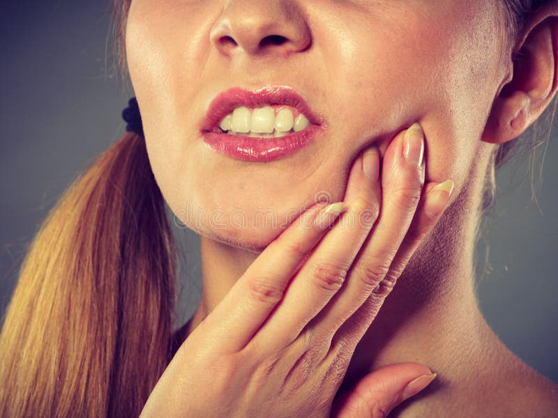 Dental care and toothache. Young woman achy girl suffering from terrible tooth pain, touching pressing her cheek by hand palm closeup. Dental care and toothache. Young woman achy girl suffering from terrible tooth pain, touching pressing her cheek by hand palm closeup