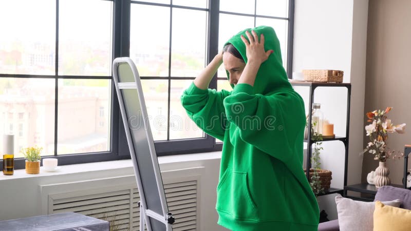 Femme souriante arrangeant des vêtements coiffure et regardant dans le miroir à la maison banque de vidéos