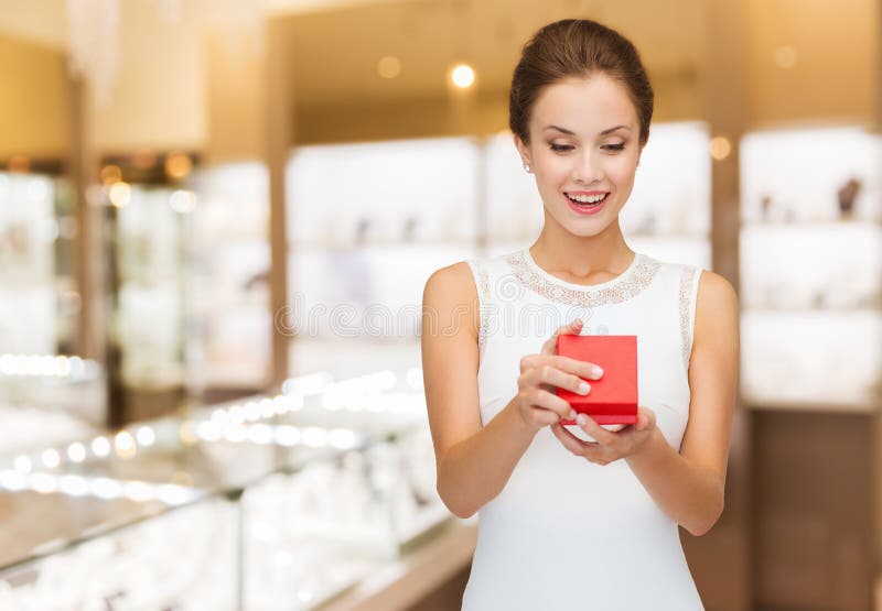 Femme souriante avec boîte cadeau rouge à la bijouterie photos stock