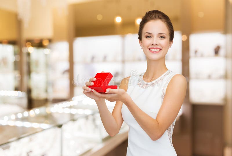 Femme souriante avec boîte cadeau rouge à la bijouterie image stock