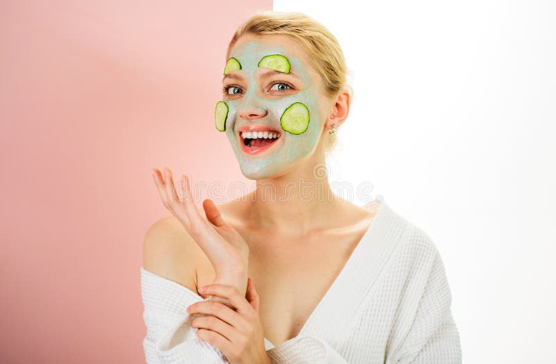 Femme souriante avec masque cosmétique en argile et tranches de concombre frais sur le visage dans le salon de spa. dermatologie d photographie stock libre de droits