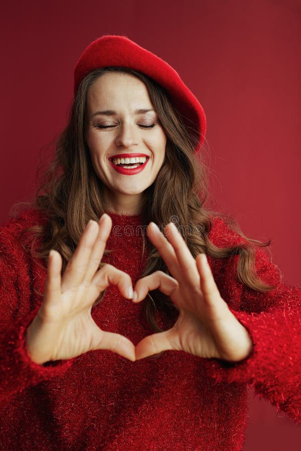 Femme souriante en chandail et béret montrant les mains du coeur photos stock