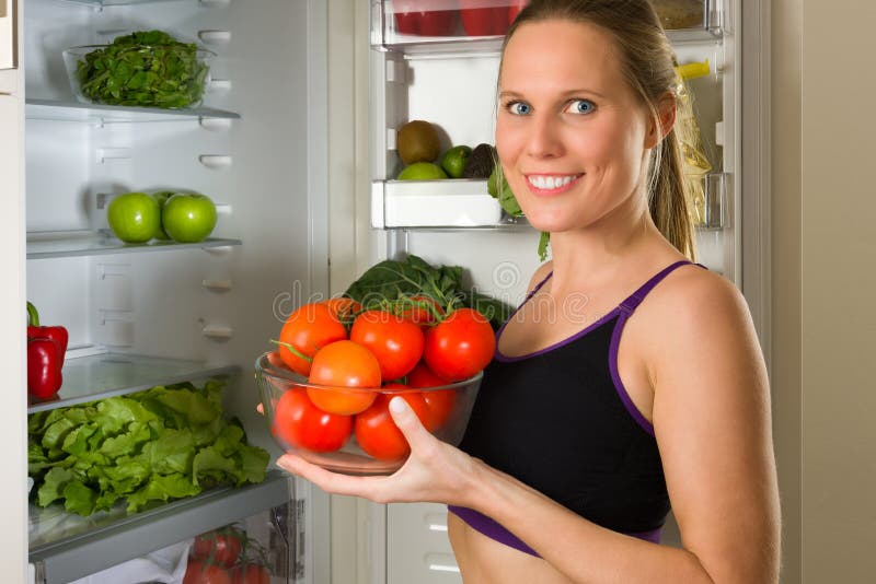 Femme sportive et caucasienne montrant des légumes pour la consommation saine images libres de droits Femme sportive et caucasienne montrant des légumes pour la consommation saine images libres de droits