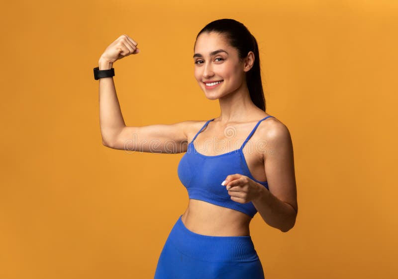 Femme sportive montrant des biceps et pointant vers la caméra images stock