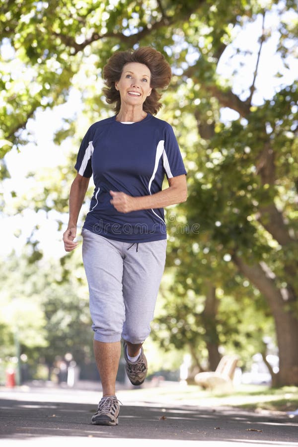 Femme supérieure courant par le parc image stock