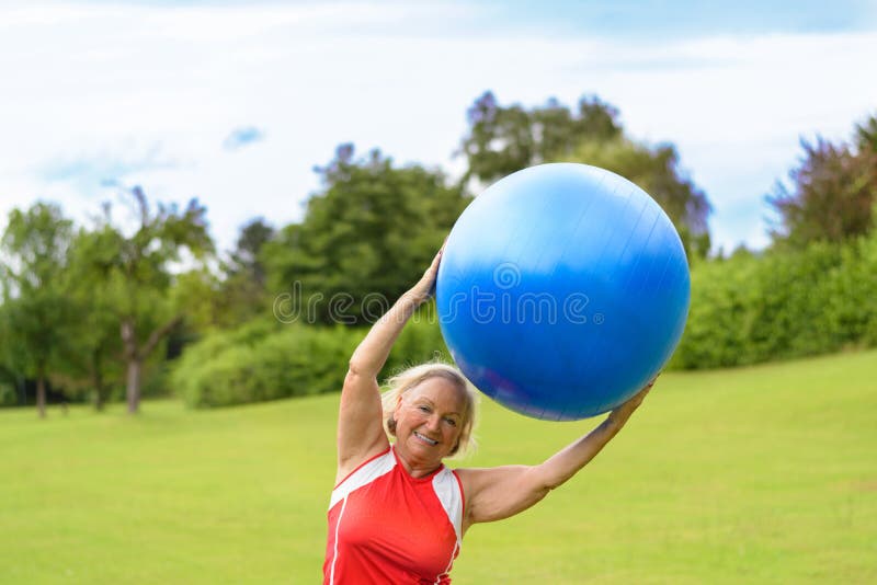 Femme supérieure heureuse avec la boule de stabilité aérienne image libre de droits Femme supérieure heureuse avec la boule de stabilité aérienne image libre de droits