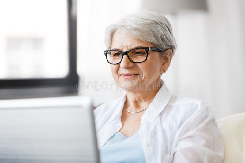 Femme supérieure heureuse avec sur l'ordinateur portable à la maison photo libre de droits Femme supérieure heureuse avec sur l'ordinateur portable à la maison photo libre de droits