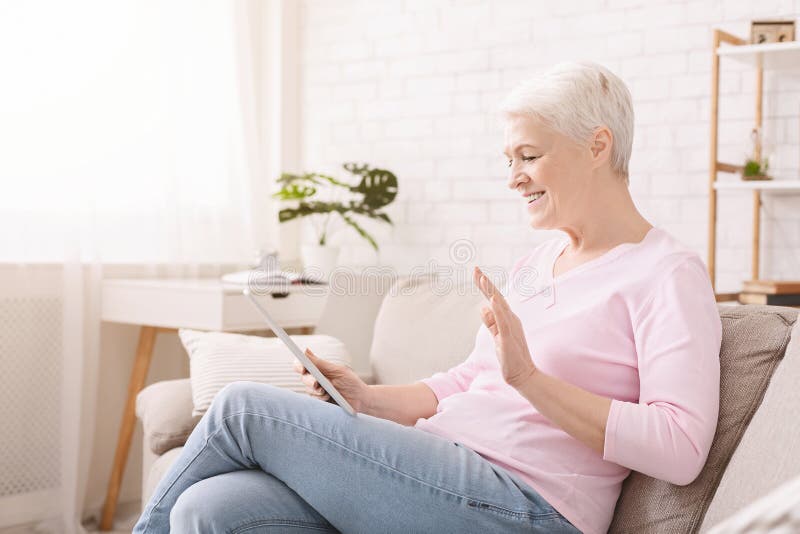 Femme supérieure heureuse parlant avec la famille par l'intermédiaire du comprimé numérique image stock Femme supérieure heureuse parlant avec la famille par l'intermédiaire du comprimé numérique image stock
