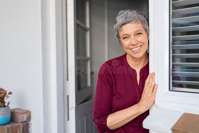 Femme supérieure heureuse se penchant à la porte