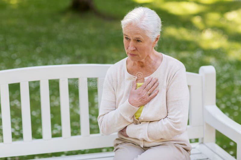 Femme supérieure se sentant malade au parc d'été photo stock Femme supérieure se sentant malade au parc d'été photo stock